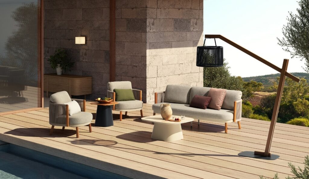 פינת ישיבה לגינת הבית בעיצוב יוקרתי עם כורסאות, ספה ושולחנות חוץ מעץ וראטן על רקע נוף טבעי.