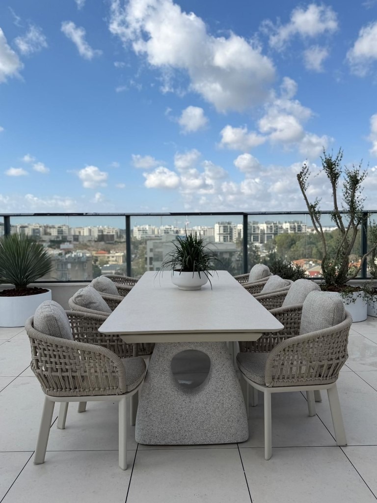 ריהוט גן מיוחד במרפסת יוקרתית עם שולחן אוכל מעוצב וכיסאות חוץ פרימיום
